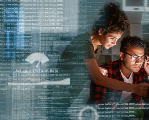Young Indian Developer And His Project Manager Discussing Application Code