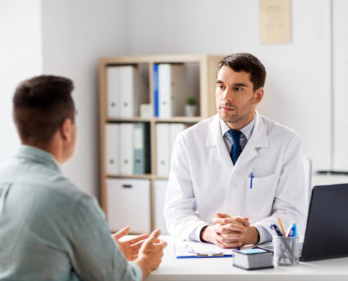 Doctor With Laptop And Male Patient At Hospital