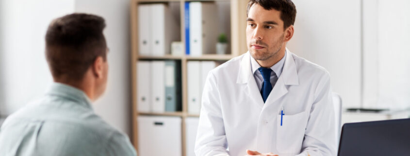 Doctor With Laptop And Male Patient At Hospital